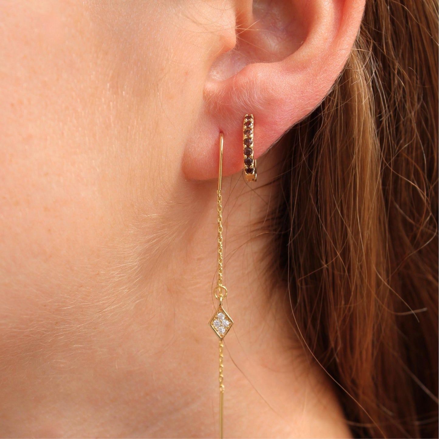 דוגמנית עונדת סט עגילים מוזהבים לאוזן עם כמה חורים – כולל חישוק, עגיל צמוד ושרשרת