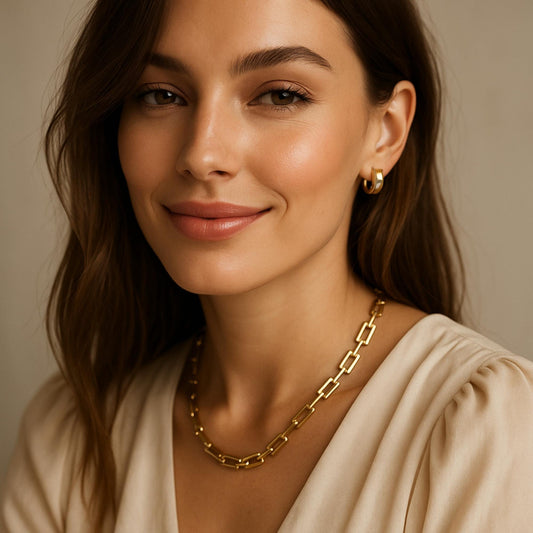 אישה לובשת שרשרת חוליות עבה מצופה זהב עם מראה אלגנטי, לבושה בגוון טבעי, בצילום סטודיו חם ונעים