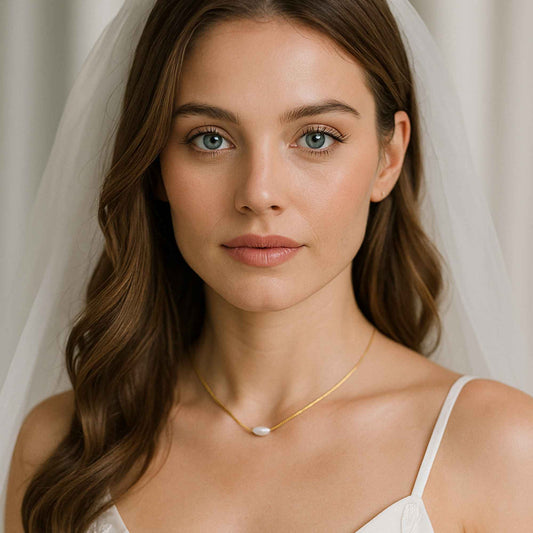 כלה  עונדת שרשרת זהב עדינה עם פנינה אובלית, בשמלת תחרה לבנה.